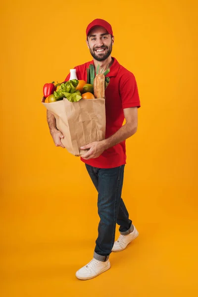 Porträt eines positiven Auslieferers in roter Uniform, der lächelt, während c — Stockfoto