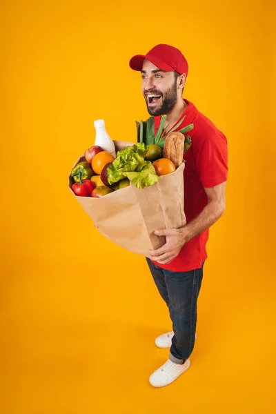 Retrato de homem de entrega sem barba em uniforme vermelho sorrindo enquanto c — Fotografia de Stock