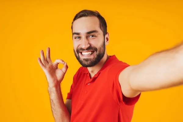 Portrait of happy man in red t-shirt laughing and showing ok sig — Stock Photo, Image