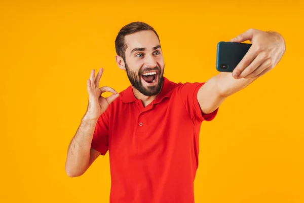 Πορτραίτο του θετικού άντρα με κόκκινο μπλουζάκι που γελάει και δείχνει εντάξει — Φωτογραφία Αρχείου
