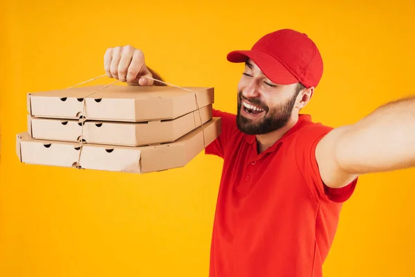 Retrato del repartidor positivo en uniforme rojo sonriente y hol — Foto de Stock