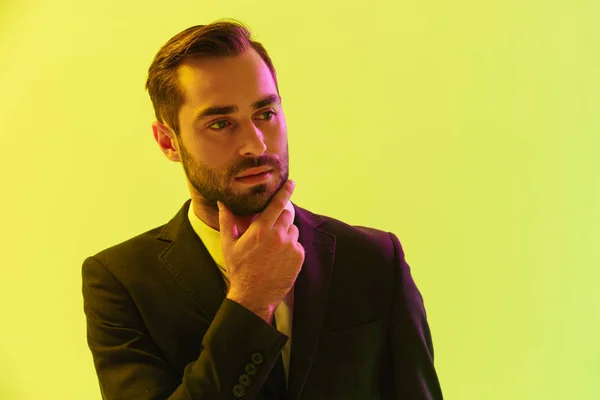 Imagen de un joven empresario con traje formal tocándose la barbilla y mirando a un lado — Foto de Stock