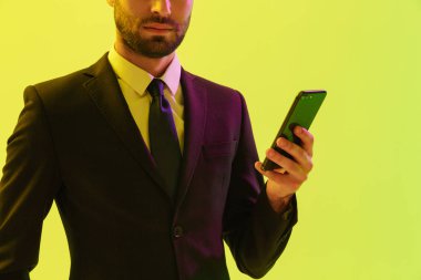 Cep telefonu tutan resmi takım elbise sakallı genç işadamı kırpılmış görüntü