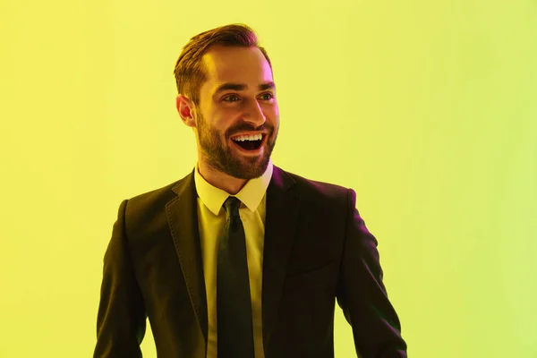 Imagen de joven empresario excitado en traje formal sonriendo y regocijándose — Foto de Stock