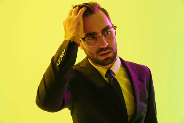 Bonito jovem homem de negócios sério posando isolado sobre a parede de fundo verde claro com luzes de néon led . — Fotografia de Stock