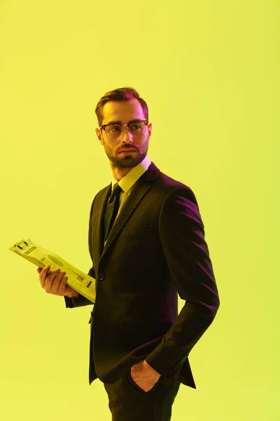 Atractivo hombre de negocios joven y atractivo concentrado posando aislado sobre la pared de fondo verde claro con luces de neón led que sostienen notas de escritura del portapapeles . — Foto de Stock