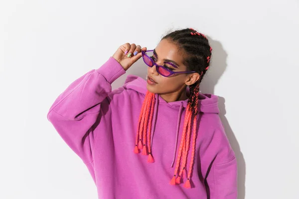 Junge Afrikanerin isoliert über weißem Wandhintergrund in leuchtend rosa Sweatshirt mit Sonnenbrille — Stockfoto