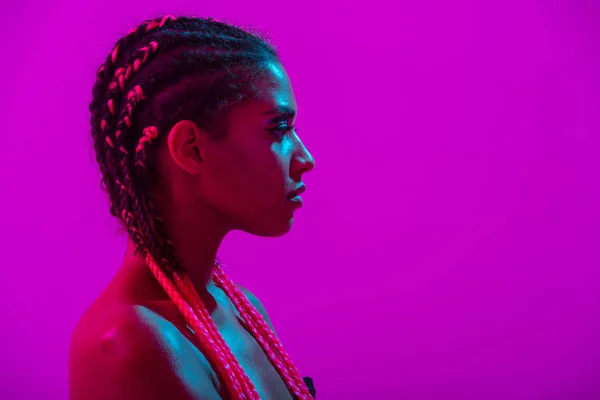 Giovane africana donna nuda posa isolata su viola neon luci parete fondo — Foto Stock