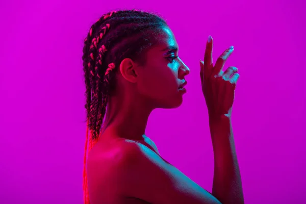 Giovane africana donna nuda posa isolata su viola neon luci parete fondo — Foto Stock