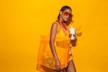 Güneş gözlüğü takan ve elinde plastik bardak tutan genç Afro-Amerikan kadın görüntüsü