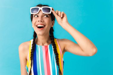 Açık ağız ile bir kenara bakarak güneş gözlüğü takan esmer şaşırtan kadın Görüntü