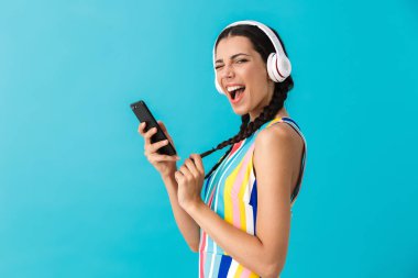 Kulaklık ve cep telefonu kullanırken pigtails göz kırpma ile esmer güzel kadın Görüntü
