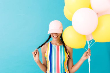 Hava balonları tutarken copyspace aşağı bakarak kap giyen sevimli gülümseyen kadın Görüntü