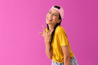 Güzel neşeli kadın geri gülümseyerek ve kaya işareti gösteren şapka giyen fotoğraf