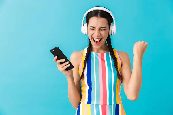 Imagen de mujer morena encantada usando auriculares y teléfono celular —  Fotos de Stock