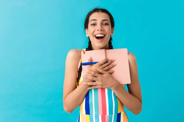 Bild einer entzückten glücklichen Frau, die in die Kamera blickt, während sie Stift und Tagebuch in der Hand hält — Stockfoto