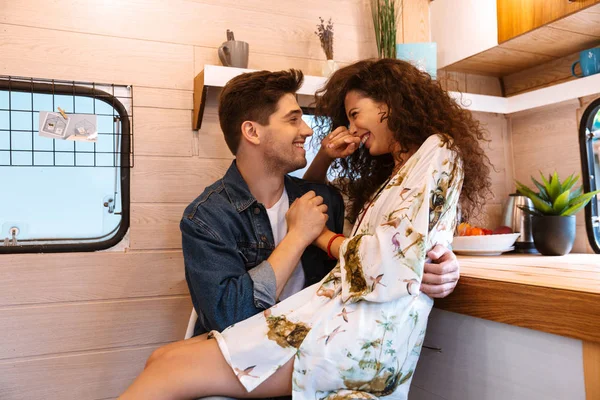 Pareja hombre y mujer sonriendo mientras se abraza en casa móvil remolque . — Foto de Stock