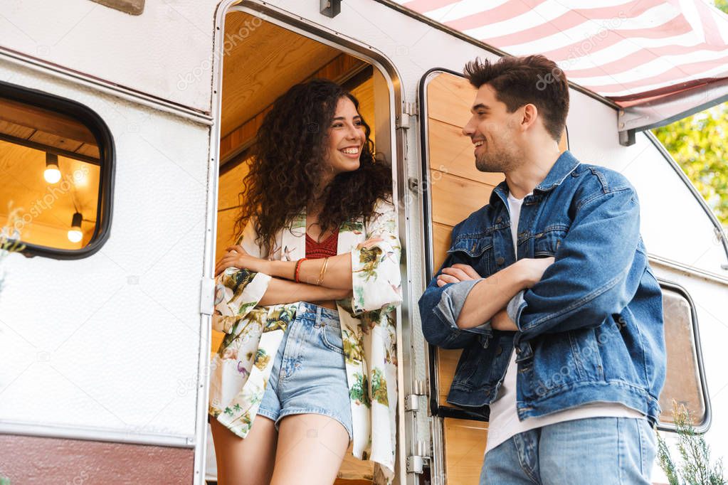 Cheerful young couple talking while standing at the campvan