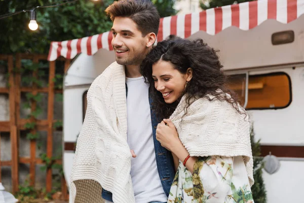 Romántico lindo pareja amorosa positiva hombre y mujer abrazando cerca de casa móvil remolque en cuadros . — Foto de Stock