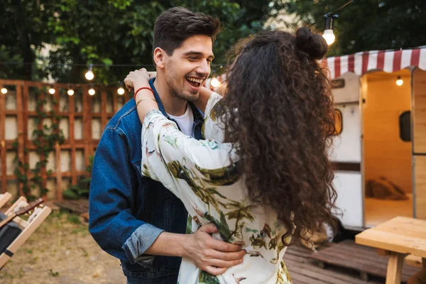 Retrato de pareja encantadora mientras bailan juntos cerca de casa sobre ruedas al aire libre — Foto de Stock