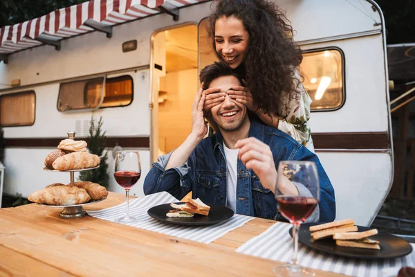 Ritratto di donna bruna sorridente che copre gli occhi del suo ragazzo a cena vicino al rimorchio all'aperto — Foto Stock