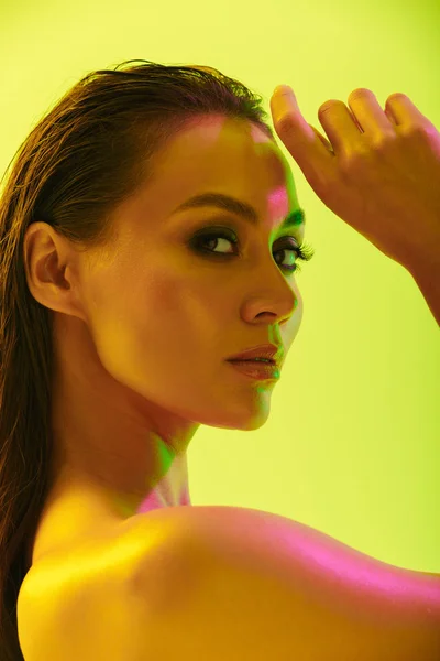 Szép, fiatal nő jelentő elszigetelt sárga fal háttér neon élénk fények. — Stock Fotó