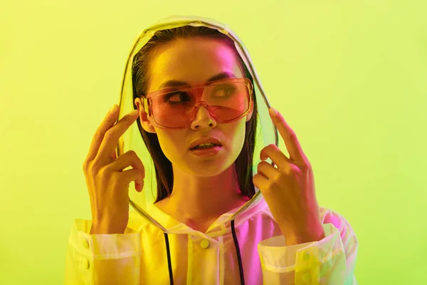 Amazing young woman posing isolated over yellow wall background with neon bright lights wearing fashion sunglasses. — Stock Photo, Image