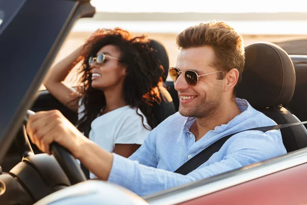 Hermosa joven pareja multiétnica cabalgando en un convertible —  Fotos de Stock