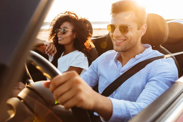 Beautiful young multiethnic couple riding in a convertible — Stock Photo, Image