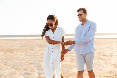 Genç çok ırklı çift gülümseyen ve el ele tutuşan fotoğraf