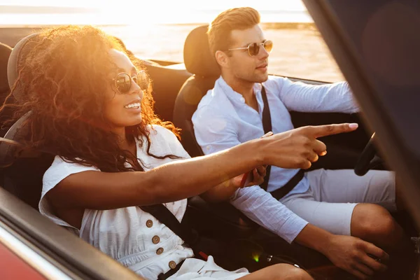 Beautiful young multiethnic couple riding in a convertible — Stock Photo, Image