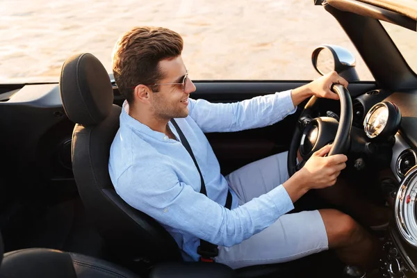 Foto de hombre caucásico feliz conduciendo un coche convertible junto al mar —  Fotos de Stock