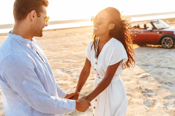 Photo of cheerful multiethnic couple holding hands together whil — Zdjęcie stockowe