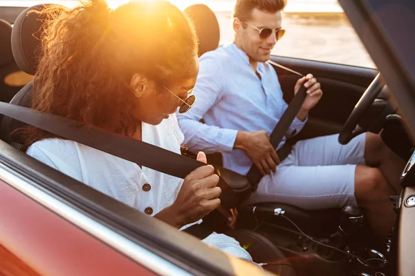 Bild av unga multietniska par som bär säkerhetsbälten medan körn — Stockfoto