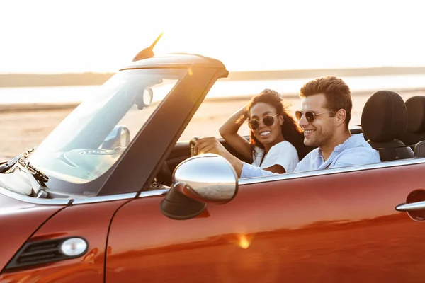 Imagen de una joven pareja multiétnica sonriendo mientras conduce converti —  Fotos de Stock