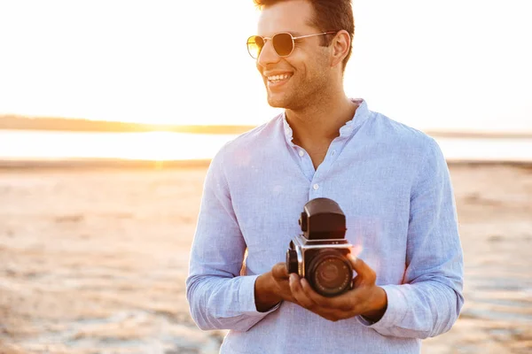 Foto dell'uomo caucasico gioioso che tiene la macchina fotografica retrò mentre cammina — Foto Stock