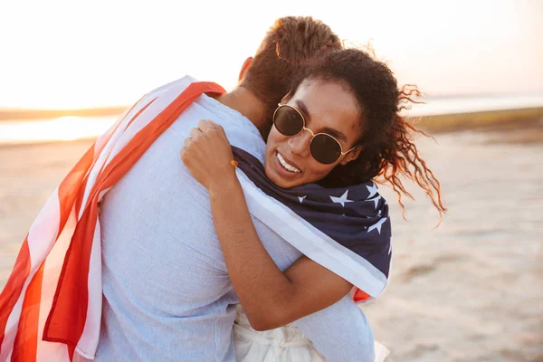 Foto di amorevole coppia multietnica avvolta nell'odore della bandiera americana — Foto Stock