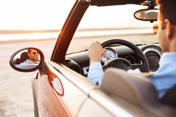 Foto di un uomo bello gioioso che guida un'auto cabriolet al mare — Foto Stock