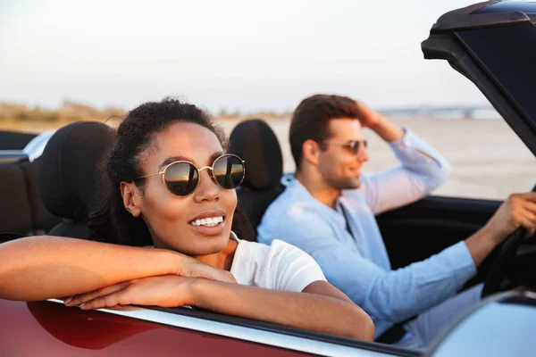 Wizerunek młodej pary wieloetnicznej uśmiechając się podczas jazdy w ConVer — Zdjęcie stockowe