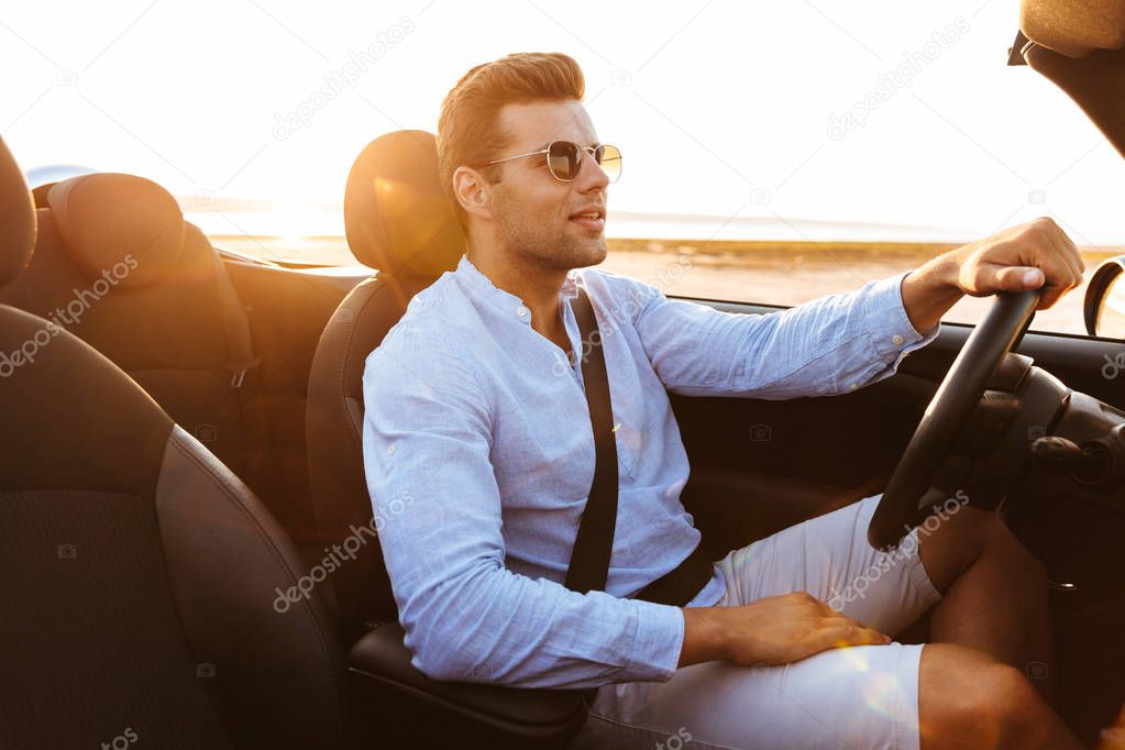 Photo of beautiful caucasian man driving convertible car by seas