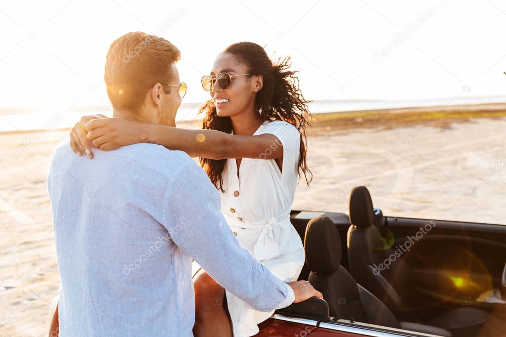 Photo of cheerful multiethnic couple hugging and smiling togethe