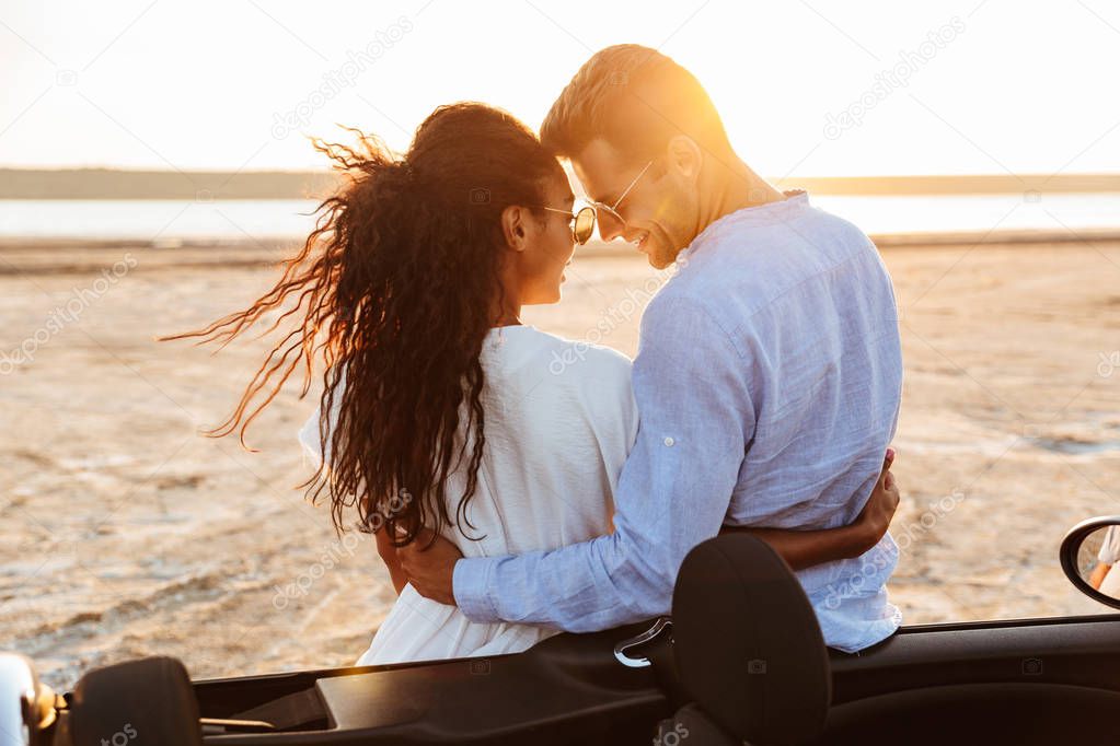 Photo from back of adorable multiethnic couple hugging together 