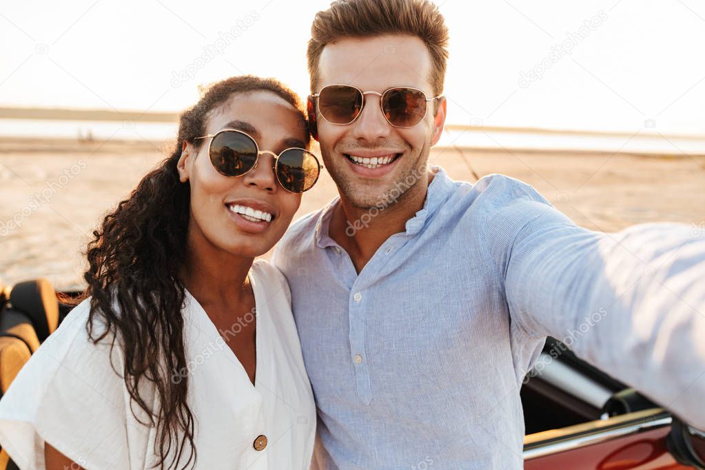 Photo of attractive multiethnic couple wearing sunglasses taking