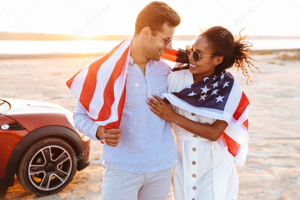 Photo of stylish multiethnic couple smiling and holding american