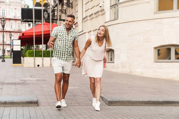 Immagine di una giovane coppia sorpresa che guarda da parte mentre cammina per strada — Foto Stock