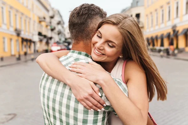 Bild eines glücklichen jungen Paares, das zusammen lächelt und sich umarmt, während es durch die Straßen der Stadt läuft — Stockfoto