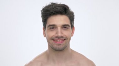 Beyaz arka plan izole üzerinde kameraya bakarken çıplak gövde gülümseyen ve göz kırpan neşeli genç esmer adam yakından görünümü