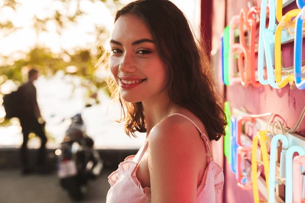 Fröhlich lächelnde junge hübsche Frau auf der Strandparty in der Nähe der hell geführten bunten Wand in der Café-Bar. — Stockfoto