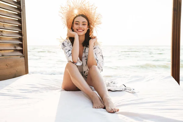 Erfreut fröhlich lächelnd junge schöne Frau am Strand posiert mit Hut. — Stockfoto