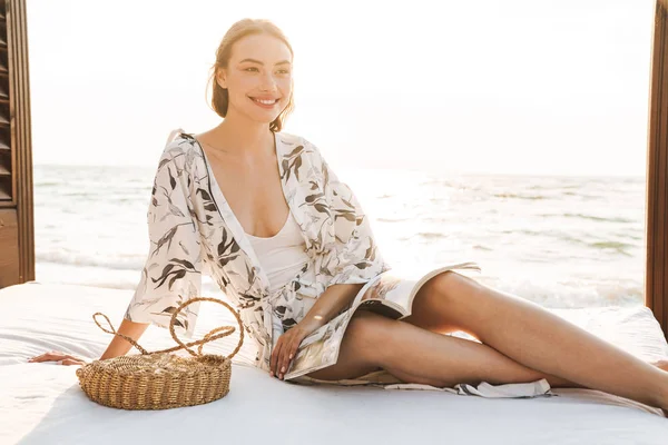 아름다운 화창한 아침 독서 잡지에서 해변에서 기쁘게 젊은 아름다운 여자. — 스톡 사진